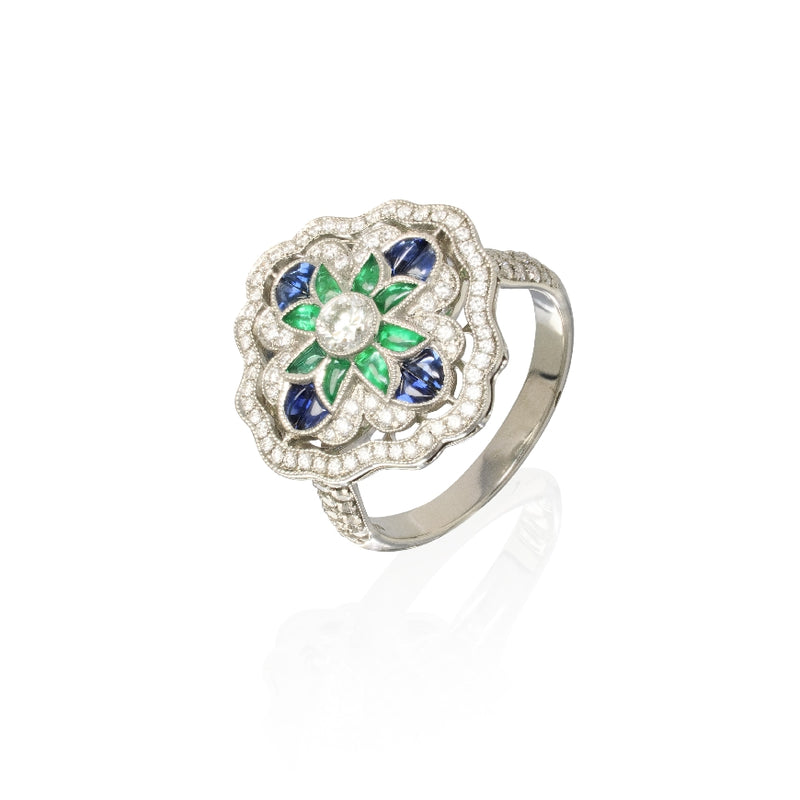 Lady's platinum deco style clover ring. Ring was crafted in platinum and consists of one center round diamond at 0.20cttw G,VS, 8 special cut blue sapphires at 0.54cttw, 8 special cut emeralds at 0.46cttw and 106 round diamonds throughout the setting