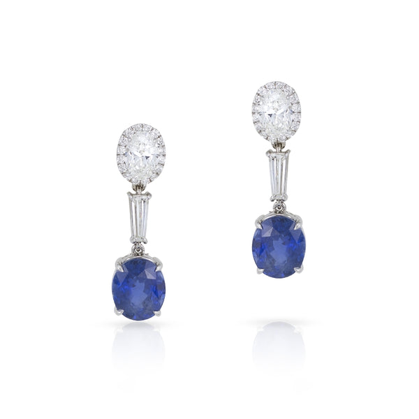 18k white gold drop earrings. Each earring has one oval diamond and halo in the first layer, the second layer contains one tapered baguette, and the third layer contains one oval Sri Lankan Sapphire Royal Blue color. There is 2.69 cttw of diamonds th